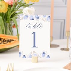 the table numbers are displayed in front of flowers and watermelon slices, along with candles