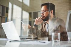 a man sitting at a table with a laptop computer in front of him and looking at the screen