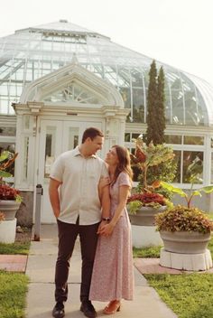 a man and woman standing next to each other in front of a greenhouse