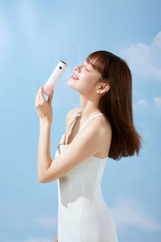 a woman holding an electronic device in her right hand and looking up into the sky