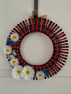 a wreath made out of red, white and black strips with daisies on it