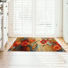 an area rug with flowers on it in front of a kitchen door and window shutters