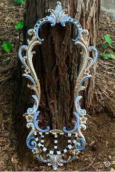 an ornate blue and white mirror next to a tree