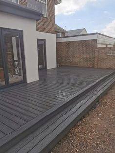 a wooden deck in front of a house with sliding glass doors on the outside side