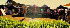 people are standing in the grass at an outdoor market