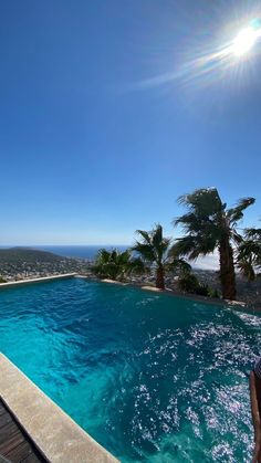 an empty swimming pool with palm trees and the sun shining on it's horizon