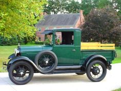 an old green truck parked in front of a house