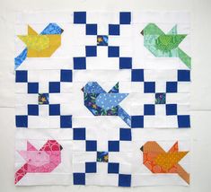 a quilted wall hanging with different colored birds and arrows on it's sides