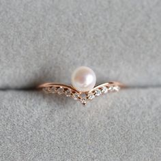 a pearl and diamond ring sitting on the ground