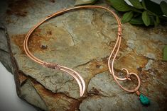 "This asymmetrical neck torc is designed so that the larger spiral with the Turquoise drop sits centrally and the other end is off center Made with very thick gauge wire, I start by hand shaping the piece, which has a double band of wire, finished with a hammered spiral design. I then begin the long process of carefully hammering the copper wire all the way round, so that it is evenly shaped. Then the spirals and sweeps are hammered, to flatten the wire and shaped, to give them a slight curve, so that it sits comfortably. The hammering not only adds detail, but it also hardens the piece into shape. The wires are wrapped together at 4 points with thinner wire which I have finished with spirals. Once the shaping of the torc is complete, I begin filing and sanding, so that the ends are perfec Copper And Turquoise, Wire Tutorials, Pendant Tutorial, Wire Jewelry Tutorial, Pagan Jewelry, Spiral Design, Neck Piece, Hand Shapes, The Wire