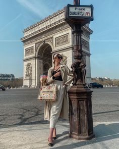 a woman standing in front of the arc de trioe with her purse and shopping bag