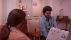 a man sitting on top of a chair next to a woman in a living room