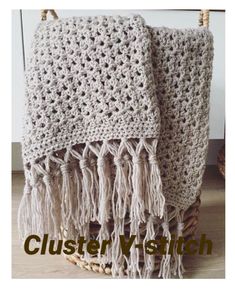 a white crocheted blanket sitting on top of a wooden floor next to a basket