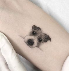 a small black and white dog tattoo on the right side of the leg, with an eye