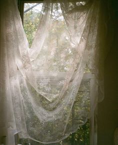 an open window with white lace curtains in it