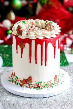 a christmas cake with white frosting and red icing dripping down the side on a plate