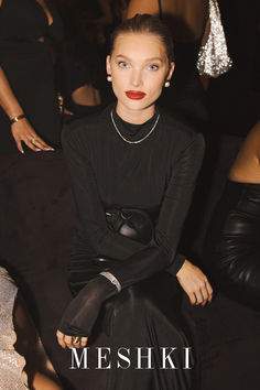 a woman sitting on top of a black couch next to other women in evening wear