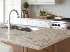 a kitchen with white cabinets and granite counter tops, an island style sink and stainless steel appliances