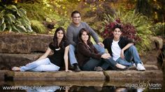 four people sitting on the edge of a body of water