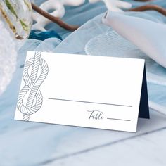 a close up of a place card on a table with napkins and flowers in the background