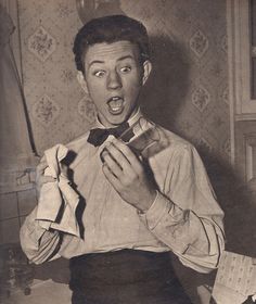 an old black and white photo of a young man wearing a bow tie with his mouth open