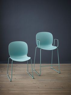 two chairs sitting on top of a wooden floor next to each other in front of a gray wall