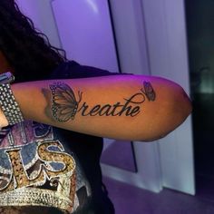 a woman with a butterfly tattoo on her arm that says breathe and butterflies are all around her