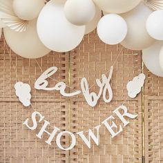 balloons and streamers with the words baby shower written on them are hanging from a bamboo wall