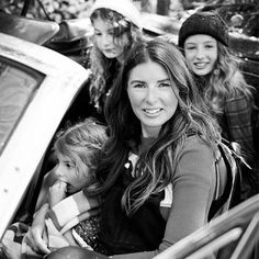 three young women are sitting in the back of a car with one holding a small child