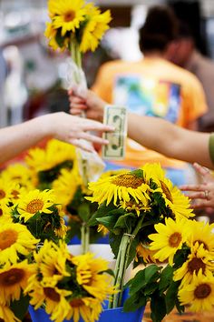 sunflowers are being given money by people at an outdoor market in the city