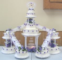 a table topped with three tiered cakes covered in purple flowers