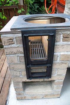 an outdoor oven built into the side of a brick wall with a grill on top