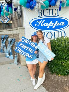 two young women holding signs in front of a blue and white sign that says buffalo kapppa road