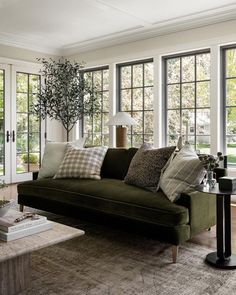 a living room filled with lots of furniture next to two large windows and a coffee table