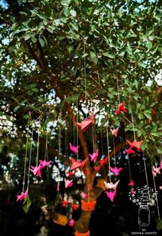 some pink origami birds hanging from a tree