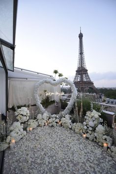 the eiffel tower is in the background with white flowers and candles around it