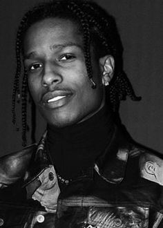 a black and white photo of a man with dreadlocks wearing a leather jacket