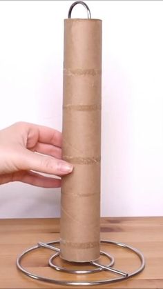 a person is holding a roll of toilet paper in front of a metal holder on a table