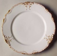 an empty white plate with gold decoration on it