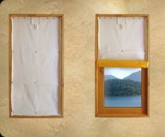 three windows with white curtains and mountains in the background