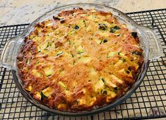 a casserole with cheese and vegetables in a glass dish on a cooling rack