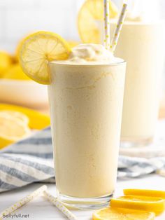 two glasses filled with lemonade and topped with whipped cream next to sliced lemons