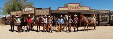 a group of men standing next to each other in front of a building with horses