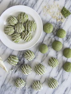 there are some green cookies in the bowl and on the table next to each other