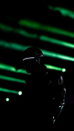 the silhouette of a person wearing a helmet and holding a cell phone in their hand