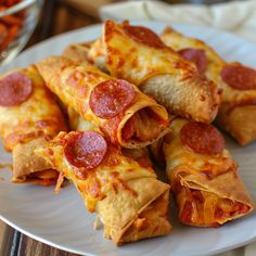 several slices of pepperoni pizza on a white plate next to some other food items