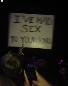 someone holding up a sign in the dark