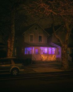 a car parked in front of a house with purple lights on it's windows