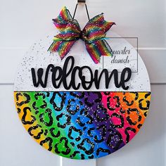 a welcome sign hanging from the side of a door with a bow on it's head