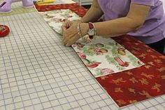 a woman is cutting fabric on a table